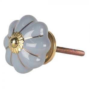 Könnte beinhalten: Ein grauer Keramik-Schrankknopf mit goldenen Akzenten und einer Messing-Schraube. Der Knopf ist blumenförmig mit einer erhabenen Mitte.