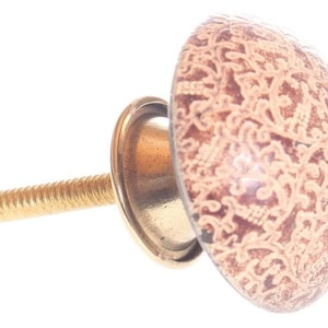 Peut inclure: Un bouton en céramique doré avec un motif floral brun et blanc. Le bouton a une vis dorée.