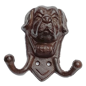 May include: A brown cast iron dog head coat hook with two hooks. The dog has a serious expression and is wearing a collar.