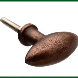 Könnte beinhalten: Ein ovaler Schrankknopf aus Kupfer mit strukturierter Oberfläche und einer silbernen Schraube.