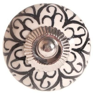 May include: White ceramic knob with a black floral design and a silver metal base.
