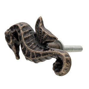 Könnte beinhalten: Ein bronzefarbener Schrank-Knopf in Form eines Seepferds mit detailliertem Design. Der Knopf hat eine Schraube auf der Rückseite zum Befestigen an einer Schranktür.