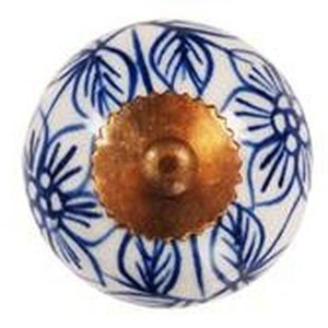 May include: A white ceramic knob with a blue floral design and a gold metal center. The knob is round and has a smooth surface.