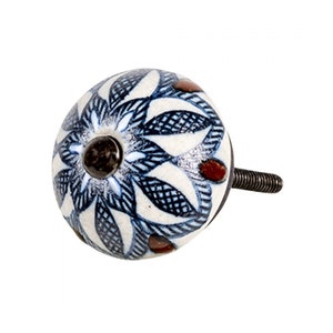 Op de afbeelding: Witte keramische knop met een blauw en bruin bloemenmotief. De knop heeft een metalen schroef.