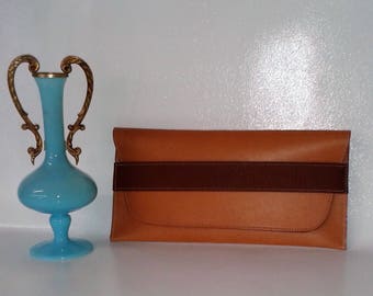 Pochette simple mais élégante en cuir vachette grainé rigide et bandeau de fermeture marron chocolat. Matériaux utilisés: Cuir