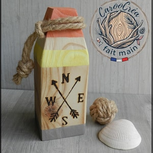 Peut inclure: Une bouée décorative en bois peinte avec des sections orange, jaune et grise, ornée d'une boussole pyrogravée avec les lettres N, S, E et W. Une corde de jute épaisse est nouée au sommet, avec un nœud en corde et un coquillage blanc.