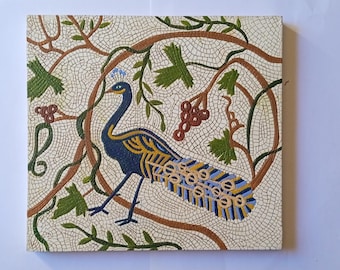 May include: A square mosaic wall art piece featuring a central blue peacock with yellow and black accents. The bird is surrounded by brown vine branches, green leaves, and clusters of red berries set against a cream-colored tiled background.