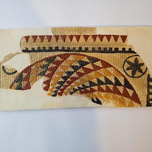 Peut inclure: Un carreau de mosaïque en gros plan avec un motif géométrique de triangles rouges, noirs, jaunes et blancs. La mosaïque a la forme d'une arche et présente un motif en forme d'étoile en haut.