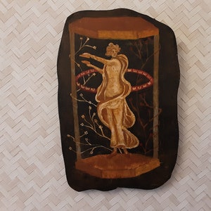 Peut inclure: Une plaque en bois peinte représentant une femme en robe blanche flottante debout dans un cadre noir avec des accents rouges et blancs. La femme est entourée de branches florales stylisées.