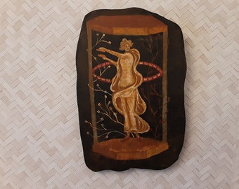 May include: A painted wooden plaque depicting a woman in a flowing white robe standing in a black frame with red and white accents. The woman is surrounded by stylised floral branches.