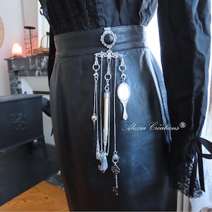 Castelaina gótica. Joya de cinturón con piedras de obsidiana y ágata negra, péndulo de adivinación, lápiz, llaves, caja secreta y espejo.