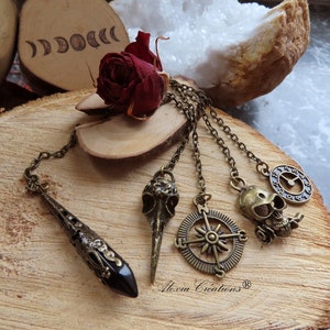 Péndulo adivinatorio con punta de Obsidiana Negra y colgante color bronce: calavera de cuervo, rosa de los vientos, reloj o calavera.