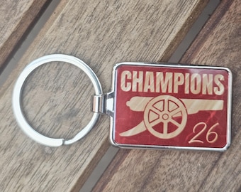 Brelok dla kibica Arsenalu Champions 2026 | Czerwono-złoty prezent sportowy | Akcesorium dla kibica piłki nożnej