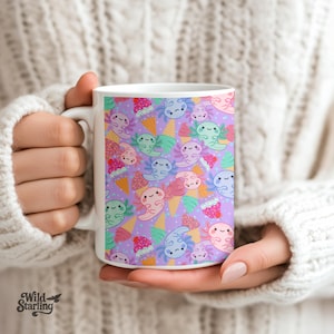 May include: White ceramic mug with a repeating pattern of cartoon axolotls and ice cream cones in pink, blue, and green on a lavender background. The mug has a white handle and the Wild Starling logo.