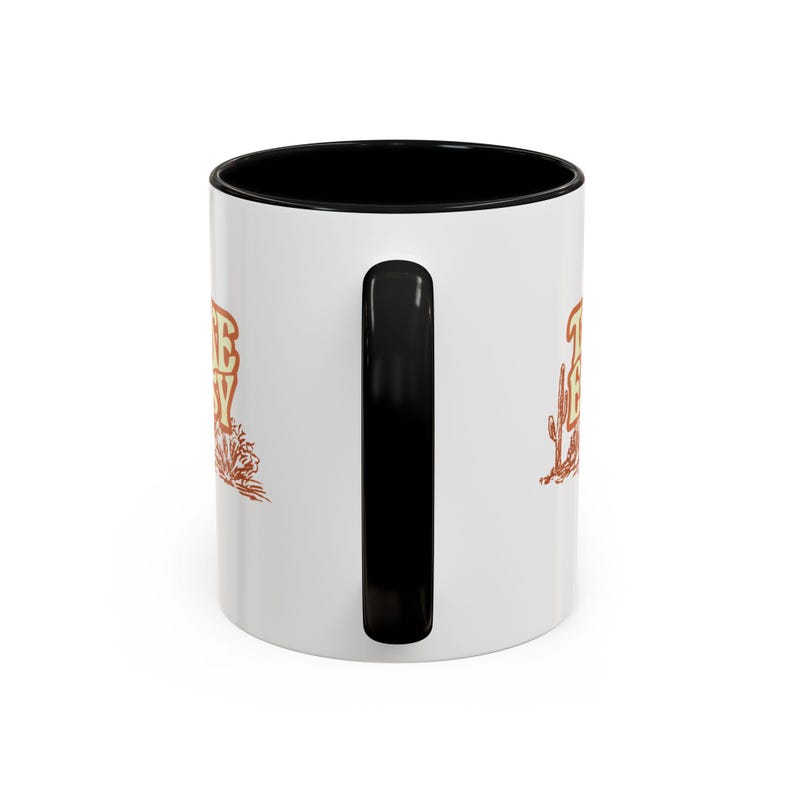 Puede incluir: Taza de cer&aacute;mica blanca con interior y asa negros. La taza presenta el texto "THE BUSY" en marr&oacute;n, con ilustraciones de cactus y follaje. Dise&ntilde;ada para bebidas calientes.