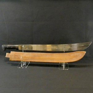 May include: A brown leather scabbard with a decorative pattern and a silver machete with a black handle.