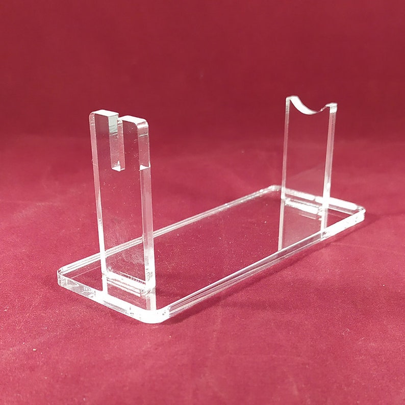 Op de afbeelding: Een transparante acryl displaystandaard voor een zwaard of ander lang object. De standaard heeft twee verticale steunen en een horizontale basis.