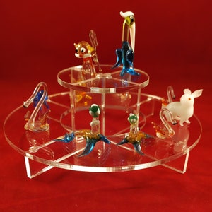 Peut inclure: Un présentoir rotatif en acrylique transparent avec une variété de figurines d'animaux en verre coloré. Les figurines comprennent un chat, un oiseau, un lapin et un champignon.
