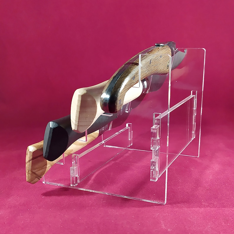 K&ouml;nnte beinhalten: Ein transparenter Acryl-Messerst&auml;nder mit zwei Messern mit Holzgriffen. Der St&auml;nder hat ein mehrstufiges Design mit einem vertikalen Trennelement. Die Messer werden mit den Klingen nach oben pr&auml;sentiert.