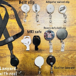 Pu&ograve; includere: Assortimento di porta badge e cordini. L'immagine mostra vari stili, tra cui clip da cintura, clip girevole a coccodrillo e modelli di clip da cintura per impieghi gravosi. Il testo "MRI safe" &egrave; visibile. &Egrave; presente anche un cordino nero con un avvolgitore.