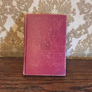 May include: A burgundy hardback book with a gold design on the front cover.