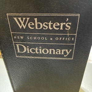 May include: A black leather-bound Webster's New School & Office Dictionary.