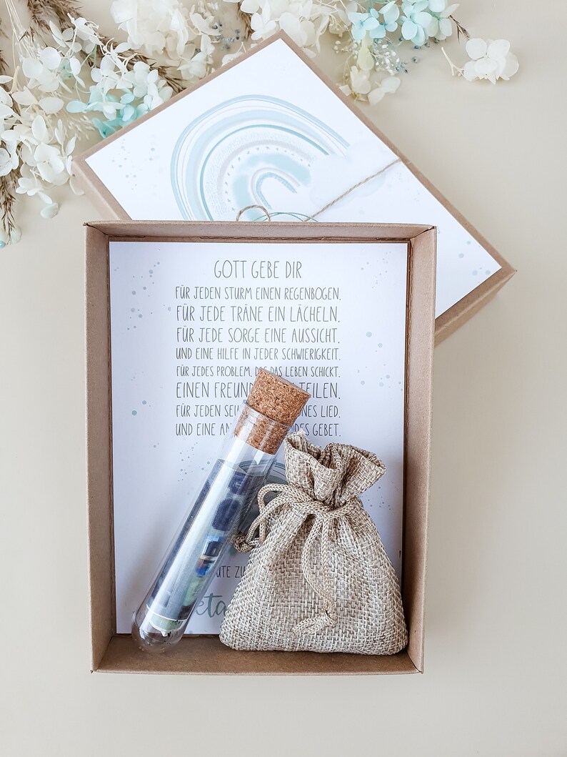 May include: A small brown burlap bag with a drawstring closure, a glass test tube filled with colorful paper scraps, and a card with the text "Gott gebe dir" and a poem in German. The card has a watercolor background with a rainbow design.