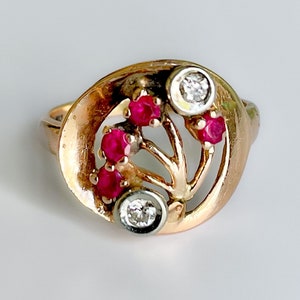 May include: A gold ring featuring a delicate, tree-like design set with five red rubies and two clear diamonds.