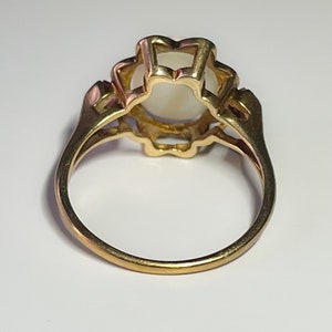 May include: A gold ring with a white opal stone set in a floral design.