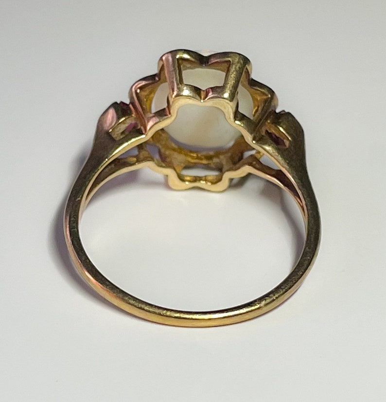 May include: A gold ring with a white opal stone set in a floral design.