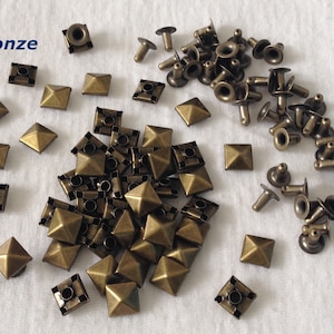 Peut inclure: Un ensemble de clous pyramidaux en bronze et de rivets métalliques. Les clous sont carrés avec un sommet en forme de pyramide. Les rivets ont une tête ronde et un axe. Le mot "Bronze" est écrit dans le coin supérieur gauche de l'image.