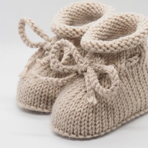 Pu&ograve; includere: Un paio di scarpine per neonati in maglia beige con un dettaglio a fiocco. Le scarpine sono realizzate in un filato morbido e caldo e hanno una vestibilit&agrave; comoda.