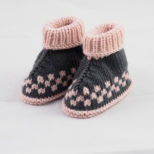 May include: A pair of gray and pink knitted baby booties with a geometric pattern.