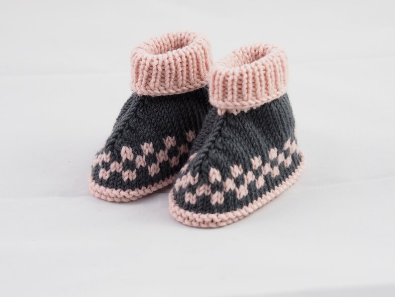 May include: A pair of gray and pink knitted baby booties with a geometric pattern.