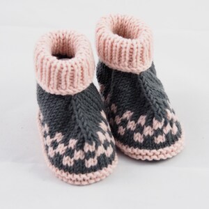 May include: A pair of knitted baby booties with a pink and gray color scheme. The booties have a pink cuff and a gray body with a pink pattern.