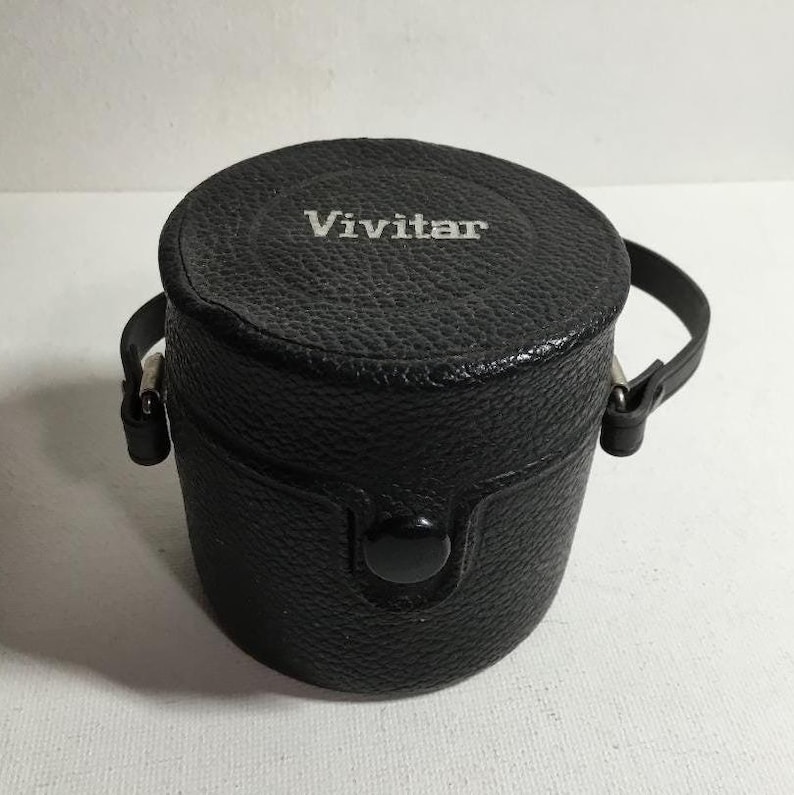 May include: Black leather camera lens case with a silver Vivitar logo and a strap.
