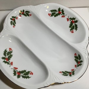 Puede incluir: Un plato de servir de cerámica blanca con tres secciones, decorado con hojas de acebo verdes y bayas rojas. El plato tiene un borde dorado.