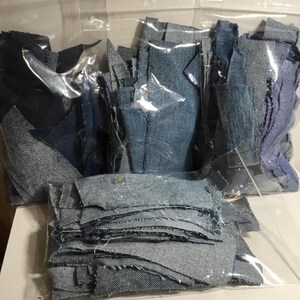 May include: Three clear plastic bags filled with various sizes and shapes of blue denim fabric scraps.