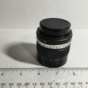 May include: A black camera lens with a silver ring and markings that read "Ultra Auto 3x Custom" and "17 8 55 4 28 2 14".