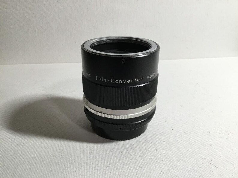 May include: A black and silver teleconverter lens with the text "Tele-Converter Model" printed on the side.