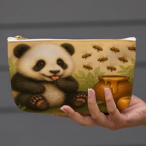 May include: A beige zippered pouch featuring a cute panda bear with its tongue out, surrounded by bees and a honey pot. The artwork has a whimsical, cartoonish style, with a golden zipper and a white border.