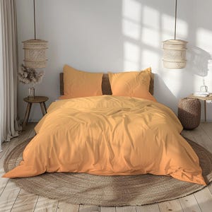 May include: A bed dressed with an orange-yellow duvet cover and two matching pillowcases. The bedding is on a wooden bed frame, with a round woven rug on the floor. Two woven pendant lights hang above the bed.