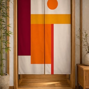 Op de afbeelding: Een rechthoekig stoffen noren-gordijn met een geometrisch ontwerp, voorzien van een groot donkerrood verticaal paneel aan de linkerkant, een centrale oranje rechthoek, een horizontale gele streep en een effen oranje cirkel op een crèmekleurige achtergrond.