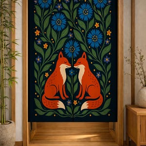 May include: A rectangular fabric door curtain featuring a dark navy background with a symmetrical illustration of two orange foxes facing each other, surrounded by green foliage, blue cornflowers, and small yellow star-shaped flowers.
