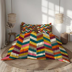 Peut inclure: Ensemble de literie à motifs chevrons multicolores. L'ensemble comprend une housse de couette et deux taies d'oreiller. Le motif présente un mélange de couleurs vives, dont le jaune, l'orange, le rose et le turquoise. Le lit est en bois.