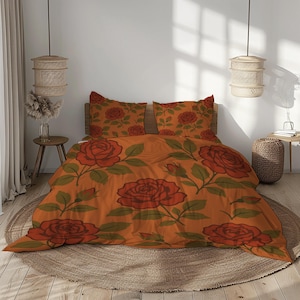 May include: An orange duvet cover and two pillowcases with a large rose pattern in red and green. The bedding is on a wooden bed frame, creating a warm aesthetic. The room is decorated with natural elements. The bedspread measures approximately 200cm x 200cm.