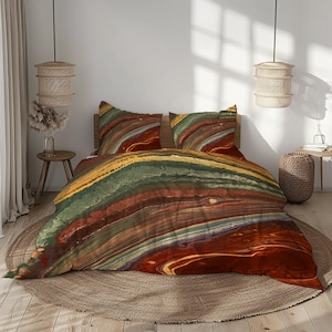 May include: A bed with a duvet cover and two pillowcases featuring a colorful, abstract design. The pattern includes bands of red, brown, green, and yellow, creating a layered effect. The bedding is set on a round, woven rug.