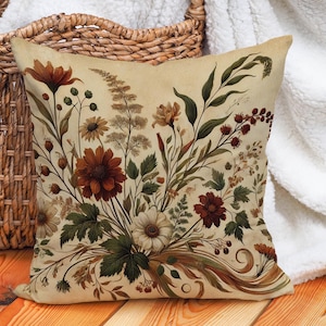 May include: A decorative throw pillow with a floral pattern featuring brown, red, and white flowers on a cream background.