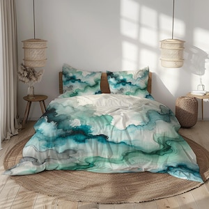 Könnte beinhalten: Ein Bett mit einem grünen und blauen Aquarell-Bettbezug und passenden Kissenbezügen. Die Bettwäsche zeigt ein wirbelndes abstraktes Muster.