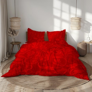 Può includere: Un completo letto rosso con motivo floreale. Il set include un copripiumino e due federe. La biancheria da letto è esposta su un letto con testiera in legno e un tappeto dai toni neutri.